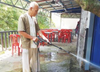 MOHD. Rais Nordin membersihkan kedai makannya yang terjejas selepas dilanda banjir kilat lewat petang semalam. – UTUSAN/NUR SHARIEZA ISMAIL