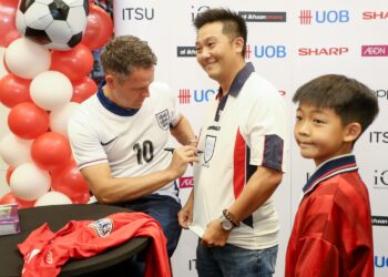 MICHAEL Owen menandatangani jersi peminatnya pada sesi bertemu peminat di AEON Mall Station 18 Ipoh hari ini. - UTUSAN