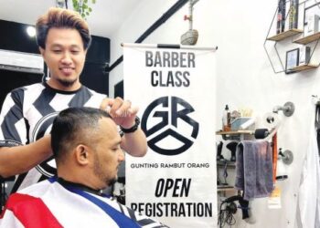 MOHAMMAD Syahrin Smail menggunting rambut pelanggan di barber Gunting Rambut Orang (GRO) di Kuala Perlis, kelmarin.- UTUSAN/MOHD. HAFIZ ABD. MUTALIB