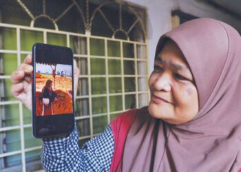 CHE Zaiton Abd. Aziz menunjukkan gambarnya ketika menziarahi pusara Zayn Rayyan.
