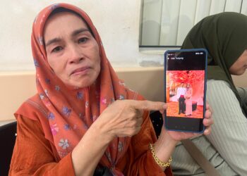 HAKIAH Nor menunjukkan gambar pasangan mangsa yang maut di Kilometer 43, Jalan Gua Musang-Lojing, Gua Musang, Kelantan hari ini.UTUSAN/AIMUNI TUAN LAH