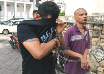 A. PRAKASH (kiri) cuba menutup wajahnya daripada dirakam lensa kamera ketika tiba di Mahkamah Sesyen dan Majistret di George Town, Pulau Pinang