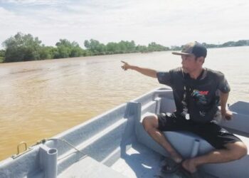 SALAH seorang menunjukkan keadaan beting pasir yang mula timbul di permukaan Sungai Perak di Teluk Intan. - UTUSAN/AIN SAFRE BIDIN