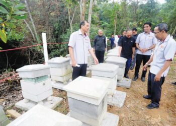 ROSLI Md. Illias (kiri) dan Bukhari Abdul Rahman (tiga dari kanan) melihat rumah lebah kelulut pada Majlis Perasmian Tapak Waqaf Bee Park di UTM, Skudai, Johor Bahru.