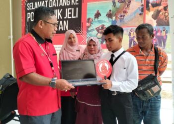 MOHAMAD Alif Haikal Wan Abdul Rahman (kiri) menerima komputer riba yang diserahkan Pengarah Politeknik Jeli, Dr. Mohd. Daud Isa (kiri) semasa mendaftar di Politeknik Jeli, Kelantan. – UTUSAN/ROHANA ISMAIL