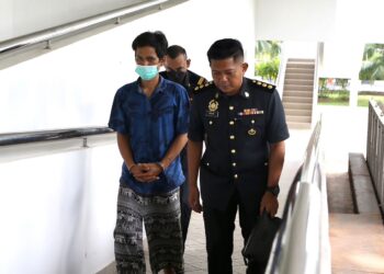 TERTUDUH, Witthaya Choochien dikawal pegawai KPDN selepas didakwa menyeleweng diesel di Mahkamah Sesyen, Alor Setar hari ini. - UTUSAN/ SHAHIR NOORDIN
