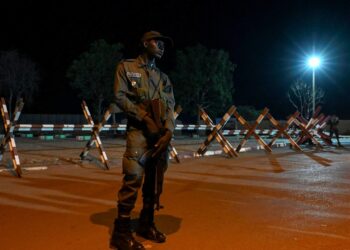 A national police officer stands guard as supporters of Niger's National Council for Safeguard of the Homeland protest outside the French and Niger airbase in Niamey on September 9, 2023 to demand the departure of the French army from Niger. The French army is holding talks with Niger's military over withdrawing "elements" of its presence there following a coup, a defence ministry source said on September 5, last year. -AFP