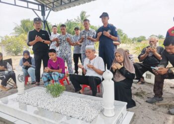 MOHD. Termizi Abdul Ghani (tengah) membaca doa di kubur anaknya ketika diziarahi anggota dan pegawai TLDM di Tanah Perkuburan Islam Batu 10, Lekir, Lumut kelmarin. – UTUSAN/AIN SAFRE BIDIN