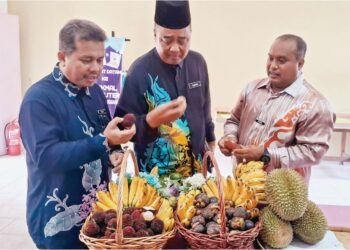 MOHD. Fadlee Hassan (kanan) menunjukkan antara buah-buahan tempatan pada Kempen Lebihkan Makan Buah-buahan dan Sayur-sayuran Tempatan di Sekolah Kebangsaan Bukit Kuang, semalam. - UTUSAN/
NIK NUR IZZATUL HAZWANI NIK ADNAN