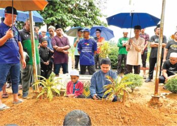 ABD. Halid Sugiman (duduk) membaca talkin tanda penghormatan terakhir untuk Hafiz Fauzan yang disemadikan di Tanah Perkuburan Islam Batu 7, Tongkang Pechah, Batu Pahat, Johor, semalam.