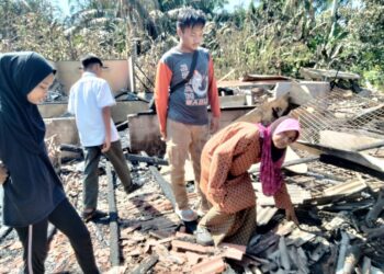RASNAH Tambi  dan tiga cucunya melihat kediaman mereka yang musnah terbakar di Kampung Parit Jerman, Telok Kerang, Pontian.