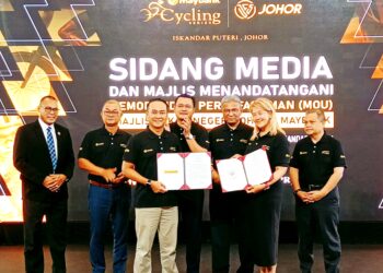 MOHD. HAIRI Mad Shah (tengah) menyaksikan pertukaran MoU antara Mohd. Ekmaluddin dengan Shazlina sempena penganjuran Maybank Cycling Series Johor, di Kota Iskandar, Iskandar Puteri.