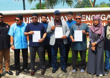 AZRUDIN Md. Idris (empat dari kiri) dan Puhat Bedol (tiga dari kanan) menunjukkan laporan yang dibuat di Pejabat SPRM Melaka di Alai, Melaka. - UTUSAN/AMRAN MULUP