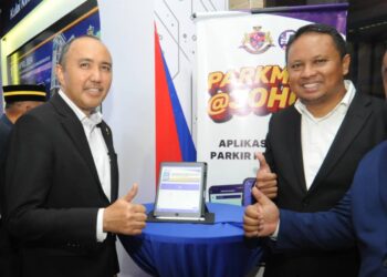 MOHD. Jafni Md. Shukor (kiri) menunjukkan tanda bagus sempena pelancaran Pendigitalan Sistem Bayaran Parkir MPKu di Ibu pejabat MPKu, Kulai.
