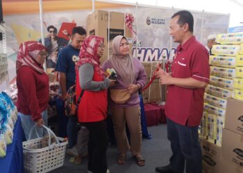 MUHAMMAD Zahir Mazlan (kanan) menyantuni orang ramai yang mengunjungi rerurai KPDN Negeri Sembilan yang mengadakan Jualan Rahmah Madani sempena NS Fest 2024 di Dataran Nilai, Seremban hari ini.-UTUSAN/NUR SHARIEZA ISMAIL.