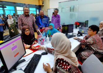 WAN AHMAD Dahlan Abdul Aziz (berdiri dua dari kiri) meninjau kaunter MyPesara dalam lawatan beliau ke Wisma Negeri di Seremban hari ini.-UTUSAN/MOHD. SHAHJEHAN MAAMIN)