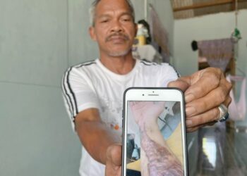 MUSTAFA Mat Zin menunjukkan gambar anaknya bersama laporan polis yang dibuat lapan tahun lalu di rumahnya di Kampung Beris Chalok, Pasir Puteh, Kelantan.