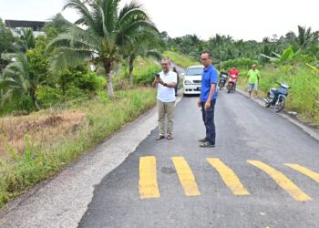 JASRI Jamaludin (kiri) meninjau jalan diturap baharu lebih kecil daripada asal sekali gus mengundang bahaya buat pengguna laluan itu terutama pada waktu malam khususnya penunggang motosikal di Kampung Sungai Jerik, Kuala Sentul di Maran, Pahang. - UTUSAN/SHAIKH AHMAD RAZIF