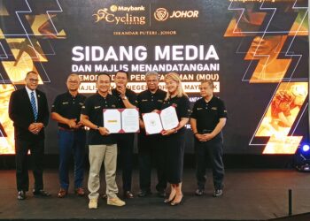 Mohd. Hairi (tengah) menyaksikan pertukaran MoU antara Mohd. Ekmaluddin dengan Shazlina sempena penganjuran Maybank Cycling Series Johor, di Kota Iskandar, Iskandar Puteri