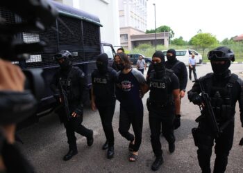 TERTUDUH (tengah) diiringi anggota polis semasa menghadiri prosiding perbicaraan di Mahkmah Kota Bharu, Kelantan hari ini-UTUSAN/KAMARUL BISMI KAMARUZAMAN.