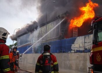 ANGGOTA bomba berusaha memadam api dalam kebakaran membabitkan beberapa buah kilang perabot di Kampung Baru Sungai Buloh hari ini. - UTUSAN/SADDAM YUSOFF