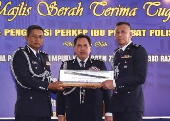 RUSDI Mohd. Isa (tengah) menyaksikan pertukaran dokumen serah terima tugas antara Noor Dellhan Yahaya (kiri) dan Nuzulan Mohd. Din pada Majlis Serah Terima Tugas di IPD Dang Wangi hari ini. - UTUSAN/M Firdaus M Johari