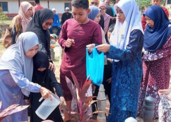 HASHNAH Ali (kiri) menjirus air mawar ke pusara anaknya, Mohamad Firdaus Yahaya di Tanah Perkuburan Islam Pongsu Seribu, Kepala Batas, Pulau Pinang.