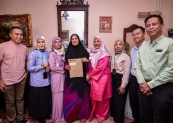 Mohamad Asri Ngosman (dua dari kanan) selepas menyerahkan faedah pencen penakat Perkeso kepada ibu Allahyarham Huzz, Noor Hamid (empat dari kiri) di Ampang Jaya, Kuala Lumpur semalam. -UTUSAN/M FIRDAUS M JOHARI