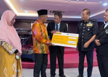 AINI Mohd. Sharif (kiri) dan suami, Ahmad Said Md. Piah (dua dari kiri) menerima sumbangan disampaikan Respa di Kuantan. – UTUSAN/NORHAFIZAN ZULKIFLI