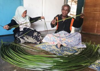 KEMAL Jani membantu Timah Upih, emproses daun mengkuang hutan untuk  dijadikan kraftangan di rumah mereka di Kampung Sungai Berua, Hulu Terengganu, semalam. - UTUSAN/NOOR HAYATI MAMAT