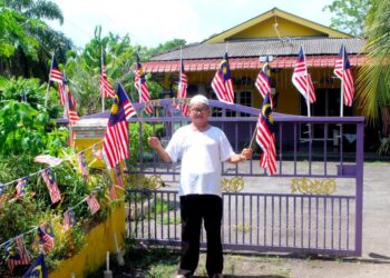 MD. KARIM Md. Yassin di laman rumahnya yang dihiasi ratusan Jalur Gemilang di Kampung Pantai, Kuala Sungai Baru, Melaka. – UTUSAN/AMRAN MULUP