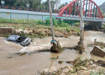 SEBUAH kereta dihanyutkan arus deras akibat kepala air di Sungai Perangin, Langkawi. - IHSAN POLIS