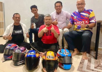 MD. Zamri (depan, tengah) memperlihatkan helmet yang pernah dipakainya sepanjang kerjaya sebagai pelumba motosikal kepada wakil HPA International (Radix) yang mengunjunginya di Klang, Selangor. - UTUSAN / ABDUL RAZAK IDRIS