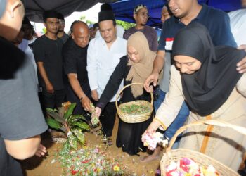 ANAK bongsu Allahyarhamah Wan Harizahtul Nadia Abu Bakar menabur bunga sambil diperhatikan abangnya  Wan Mohd Hibatullah selepas upacara perkebumian ibunya Sharifah Azizah Syed Zain di Tanah Perkuburan Islam, Kampung Tengah, Kluang disini. UTUSAN/RAJA JAAFAR ALI