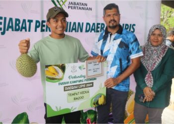 PENGARAH Pertanian Pahang, Muhd Rizal Baharom ( tengah) menyampaikan hadiah pemenang kedua durian kampung premium kepada Muhammad Rahimi Zainal Abidin di Lipis. - UTUSAN/ SALEHUDIN MAT RASAD