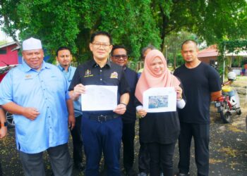 LIM Ban Hong menunjukkan pelan projek pembinaan pelantar baharu dan pemasangan mesin winch di Pangkalan Nelayan Sungai Lereh, Klebang, Melaka. - UTUSAN/AMRAN MULUP