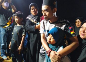 YUSOF Mokhtar kelihatan sebak sambil memeluk anak sulungnya semasa menghadiri pengebumian jenazah isterinya di perkuburan Islam Kubur Besar Bandar Pasir Mas, Pasir Mas, Kelantan-UTUSAN/ROHANA ISMAIL.