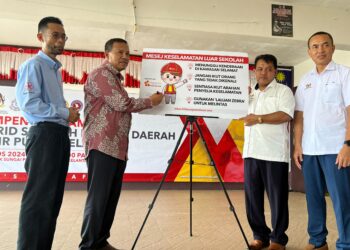 RAMLEE Patta (kiri) menyaksikan gimik perasmian Kempen Keselamatan Murid Sekolah Rendah yang disempurnakan Mohammad (dua dari kiri) di SMK Sungai Petai Pasir Puteh, Kelantan, hari ini. UTUSAN/TOREK SULONG.
