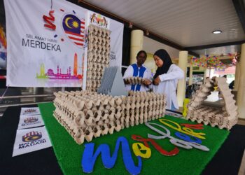 NASRUNA Rahmat (kanan) bersama rakannya, M. Saraswathy menghias rekaan replika Bangunan Parlimen yang menggunaan bekas telur ketika ditemui di kawasan R&R Seremban Arah Utara semalam.-UTUSAN/MOHD. SHAHJEHAN MAAMIN.