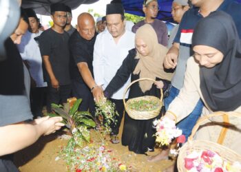 ANAK bongsu Allahyarham, Wan Harizahtul Nadia Abu Bakar (tiga dari kanan) menabur bunga sambil diperhatikan abangnya,  Wan Mohd Hibatullah selepas upacara pengebumian Sharifah Azizah Syed Zain di Tanah Perkuburan Islam, Kampung Tengah, Kluang, semalam. 
– UTUSAN/RAJA JAAFAR ALI