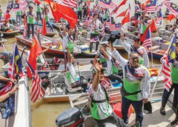 MUHAMMAD Sanusi Md Nor (depan, tengah) turut menyertai perarakan merdeka dengan mengemudi bot menyusuri Sungai Kedah dari Kampung Seberang Anak Bukit ke Muzium Negeri Kedah di Alor Setar. – MINGGUAN/SHAHIR NOORDIN