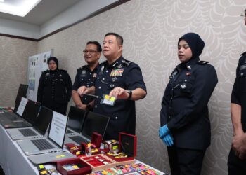 AZIZI Mat Aris menunjukkan sebahagian barang yang dirampas dalam serbuan di dua rumah yang dijadikan pusat panggilan penipuan pekerjaan tidak wujud di Taiping, kelmarin. - UTUSAN