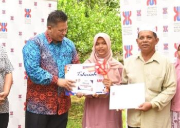 RAZLI Che Razak (dua kiri) menyerahkan surat tawaran kemasukan ke UMK kepada Harteenee Waekuechi di Kampung Dusun Nyior, Kuala Krai, Kelantan semalam.