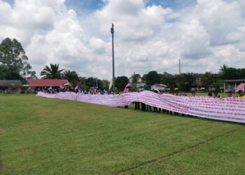 MURID dan guru SK Kampung Ayer Hitam di Teluk Intan menunjukkan kain rentang yang dicap dengan tapak tangan yang dihasilkan sempena Hari Kebangsaan. - UTUSAN/AIN SAFRE BIDIN