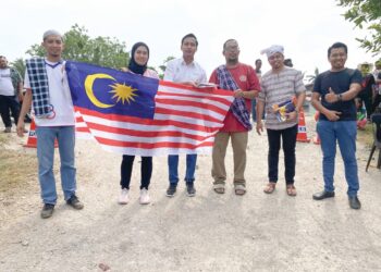 FAHMI Zainol (tiga dari kiri) menyerahkan Jalur Gemilang kepada barisan urus setia Komuniti Madani Telok Ayer Tawar dan Komuniti Madani Taman Wira di Kampung Paya, Pulau Pinang, baru-baru ini.