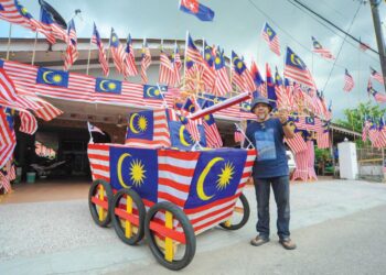 HASSRI Abdul Kadir bersama kereta kebal yang dihiasi Jalur Gemilang bagi menyambut Hari Kebangsaan ke-67 di rumahnya di Kampung Bendahara, Johor Bahru, Johor. – UTUSAN/RAJA JAAFAR ALI