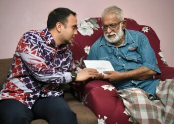 FARHAN Fauzi (kiri) ketika menyantuni Karam Singh Walian semalam sambil menyampaikan sumbangan mewakili Perdana Menteri. -IHSAN PEJABAT PERDANA MENTERI