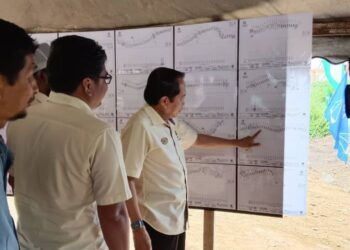 AHMAD Maslan melihat (kanan) melihat peta lokasi pembinaan jalan baharu dari simpang Ladang Serasa ke Kampung Lulut, Mukim Kuala Sungai di Gua Musang, Kelantan hari ini.