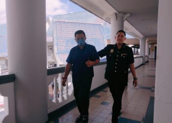 TERTUDUH diiringi pegawai SPRM ketika dihadapkan ke Mahkamah Sesyen Ayer Keroh, Melaka.