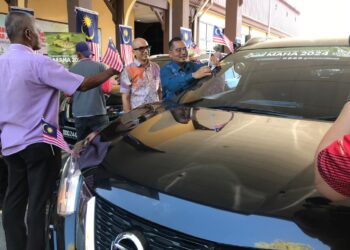 MOHD. Faizul Mustafa (kanan) melekatkan bendera pada kenderaan KADA Majlis Pelancaran Bulan Kebangsaan dan Kibar Jalur Gemilang 2024 Peringkat KADA di pejabatnya di Lundang, Kota Bharu, Kelantan hari ini.- UTUSAN/ ROSLIZA MOHAMED